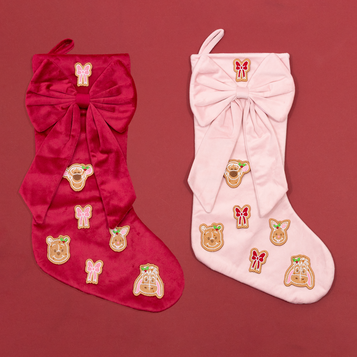 Red and pink Christmas stockings with oversized bows and Winnie the Pooh, Tigger, Piglet and Eeyore gingerbread embroidery.