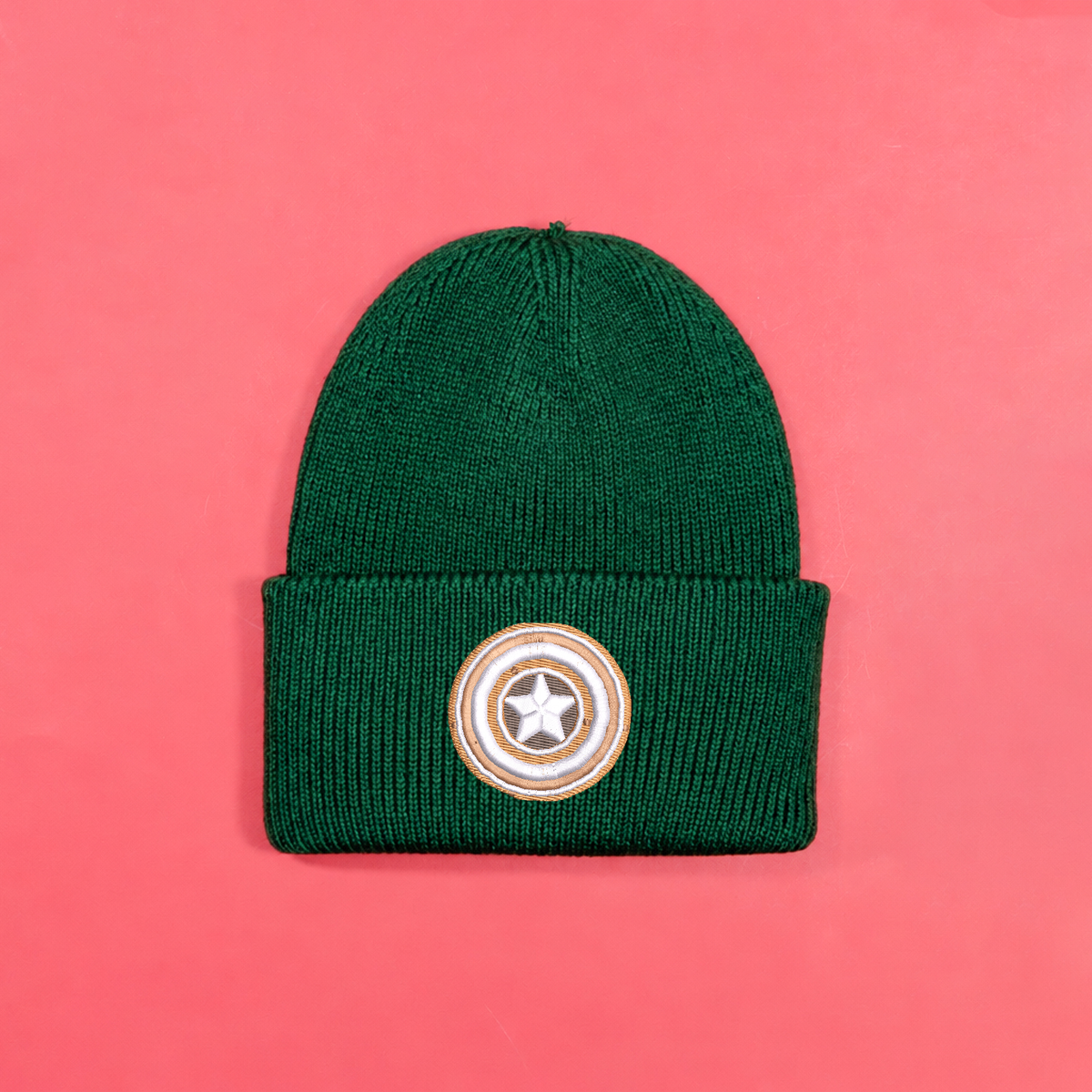 Bottle green knitted beanie with gingerbread-style Captain America shield embroidery on the turned-up cuff.
