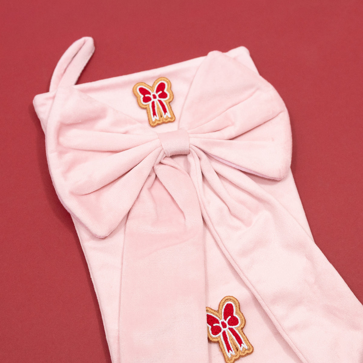 Close-up of the oversized pink bow, hanging loop and red bow embroidery at the top of the Mickey and Minnie Christmas stocking.