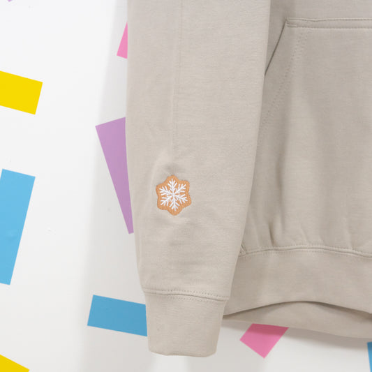 Close-up of gingerbread snowflake embroidery above the cuff of the stone superhero hoodie.