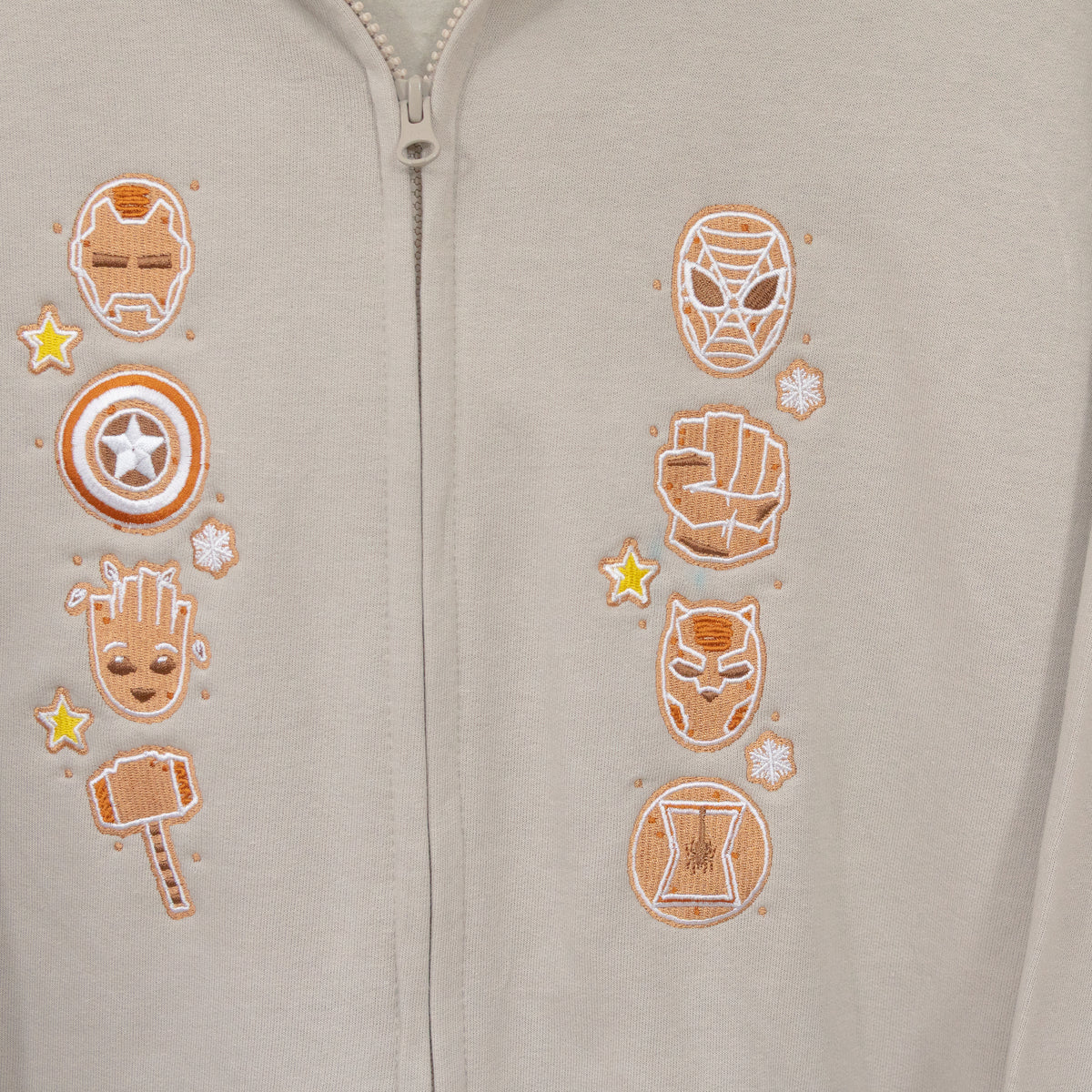 Close-up of eight gingerbread Marvel superhero designs with stars and snowflakes on either side of the stone hoodie zip.