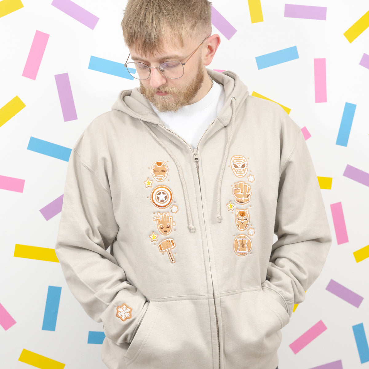 Model wearing the stone gingerbread superhero zip-up hoodie with hands in the front pockets.
