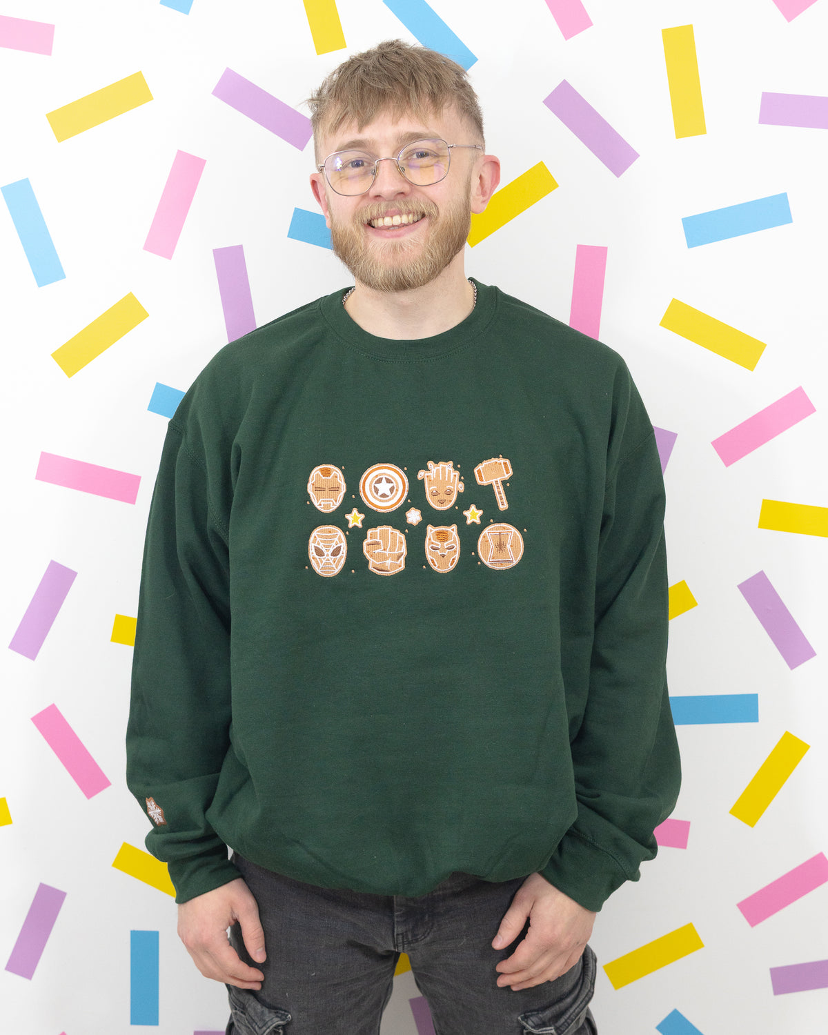 Front view of a model wearing the bottle green gingerbread Marvel crew-neck jumper.