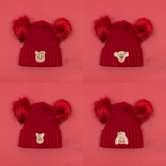Four red knitted beanies with twin fluffy pom poms, showing Winnie the Pooh, Tigger, Piglet and Eeyore gingerbread embroidery.