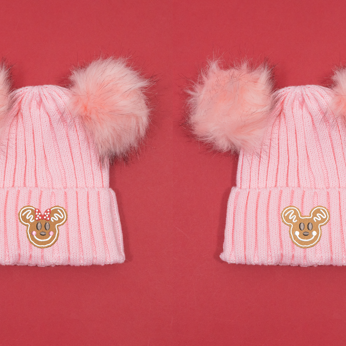 Pink knitted beanies shown side by side with Minnie and Mickey gingerbread embroidery and fluffy pink pom poms.