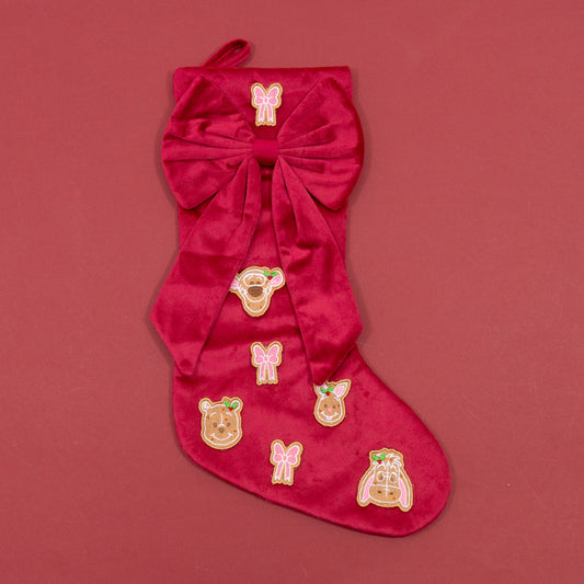 Red Christmas stocking with an oversized bow, pink embroidered bows and Winnie the Pooh and friends gingerbread faces.