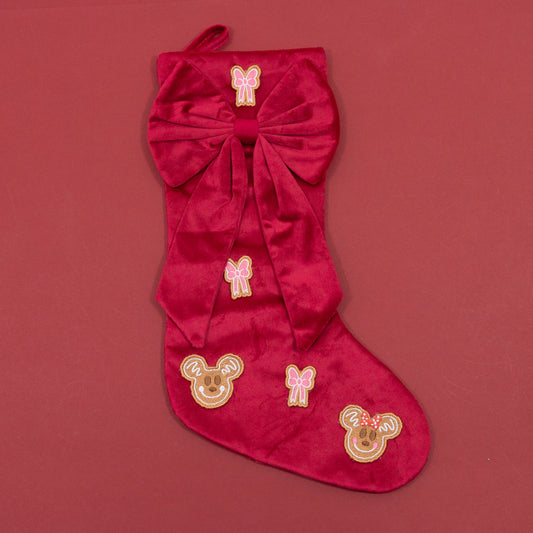 Red Christmas stocking with an oversized red bow, pink embroidered bows and Mickey and Minnie gingerbread faces.