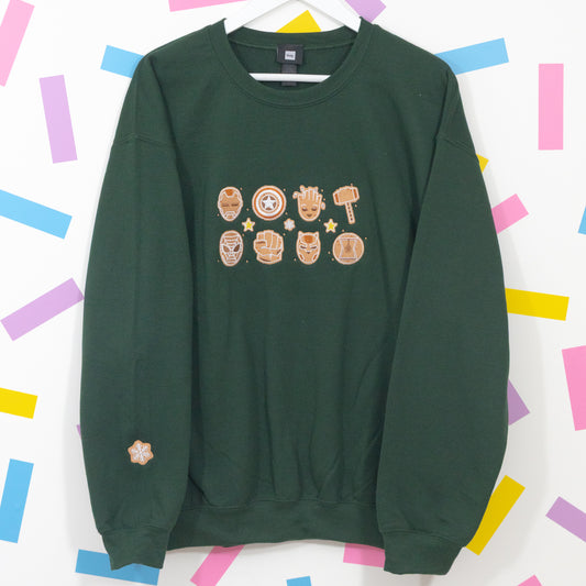 Bottle green crew-neck jumper on a hanger with gingerbread Marvel chest embroidery and a snowflake sleeve detail.