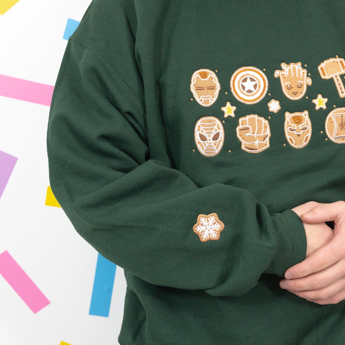 Modelled detail of the green superhero jumper showing gingerbread snowflake sleeve embroidery and chest designs.