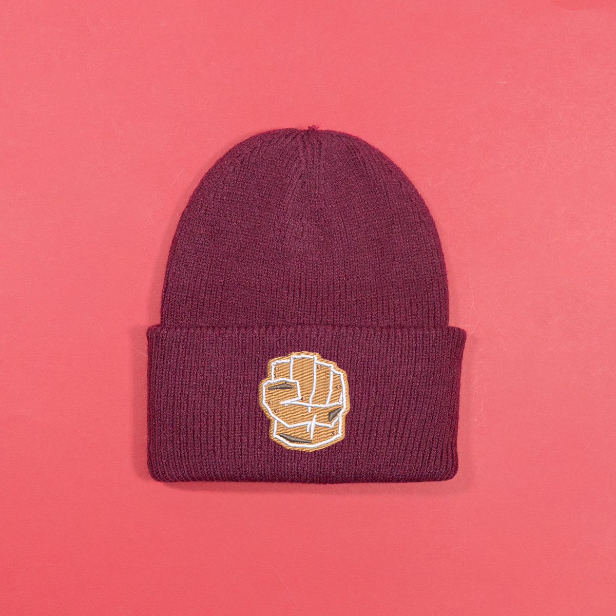 Burgundy knitted beanie with gingerbread-style Hulk fist embroidery on the turned-up cuff.
