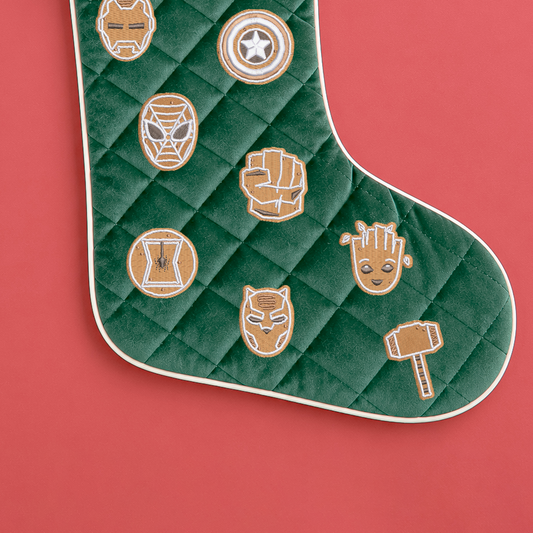Close-up of gingerbread-style Marvel embroidery on a green quilted stocking, including Groot, Spider-Man, Hulk's fist and Thor's hammer.