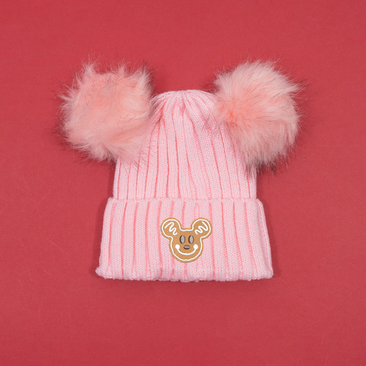 Pink ribbed knitted beanie with two fluffy pink pom poms and Mickey Mouse gingerbread embroidery on the turned-up cuff.