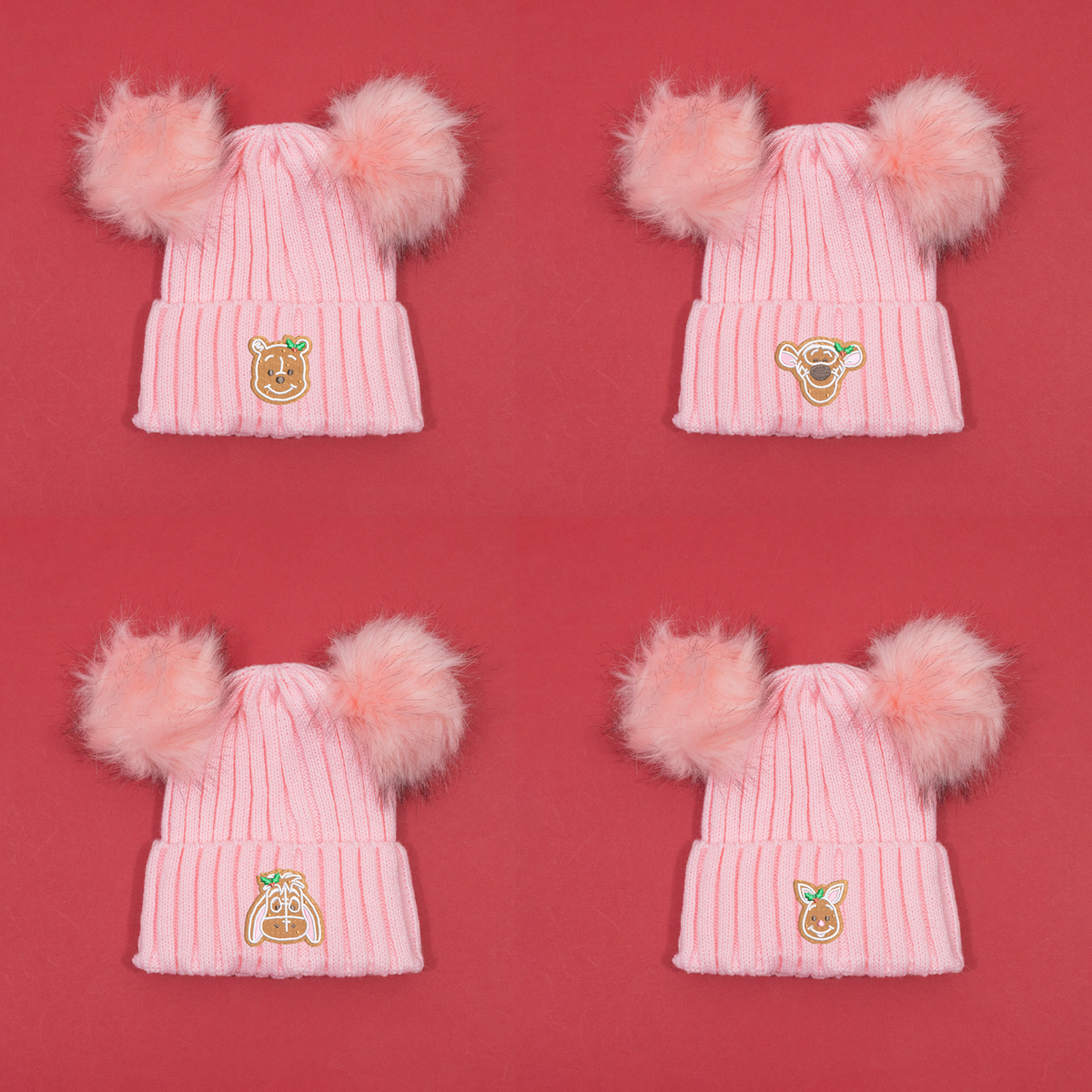 Four pink knitted beanies with twin fluffy pom poms, showing Winnie the Pooh, Tigger, Eeyore and Piglet gingerbread embroidery.