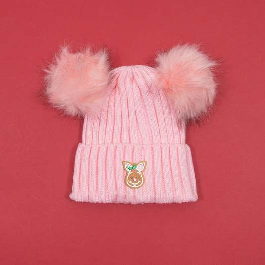 Pink ribbed knitted beanie with two fluffy pink pom poms and Piglet gingerbread embroidery with holly on the cuff.